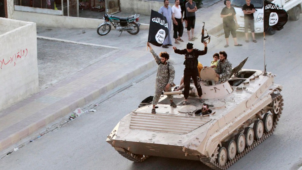 Militant Islamist fighters take part in a military parade along the streets of northern Raqqa province on June 30, 2014.