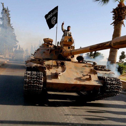 Militant Islamist fighters on a tank take part in a military parade along the streets of northern Raqqa province