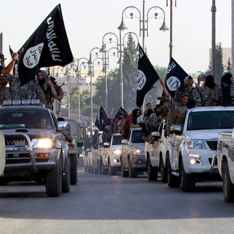 Militant Islamist fighters parade on military vehicles along the streets of northern Raqqa province June 30, 2014.