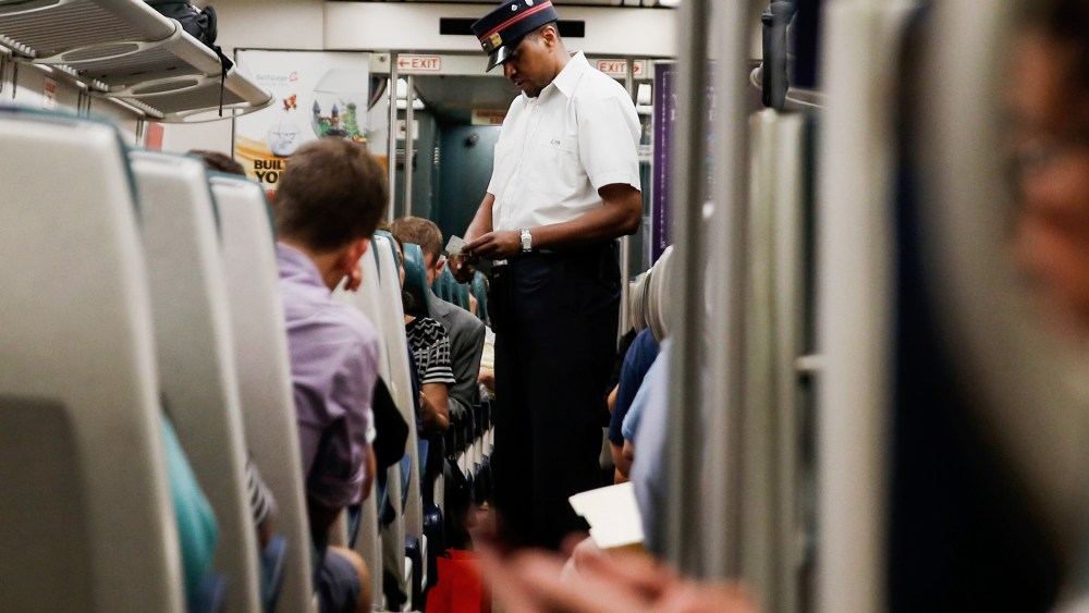 A Long Island Rail Road train conductor collects tickets aboard a train bound for Port Washington leaving Pennsylvania station in New York