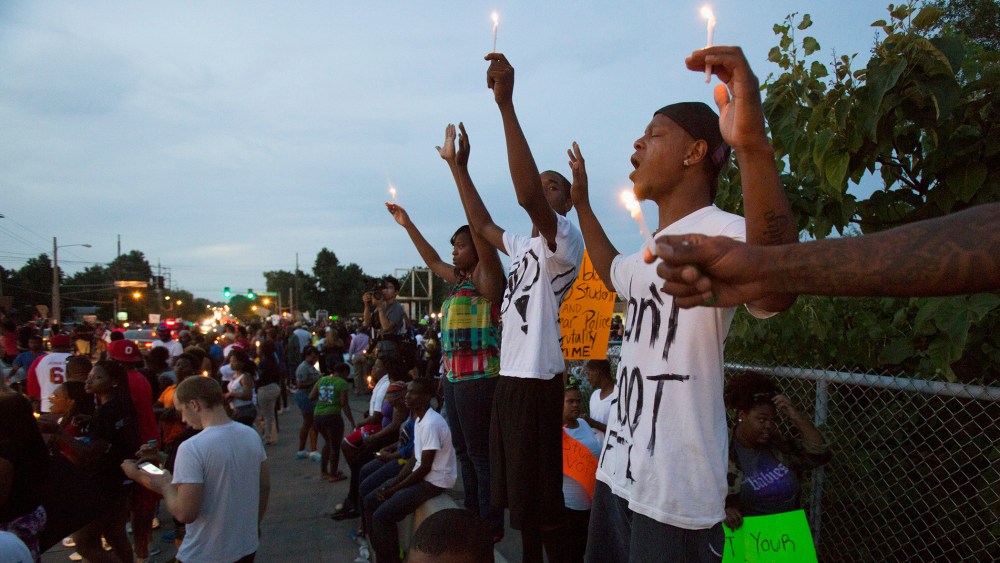 People hold candles during a peaceful demonstration, as communities react to the shooting of Michael Brown in Ferguson, Missouri August 14, 2014.