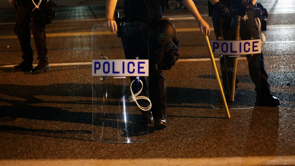 Police officers in riot gear stand in position as demonstrators protest the shooting death of Michael Brown, in Ferguson, Mo., on Aug. 19, 2014. (Photo by Joshua Lott/Reuters)