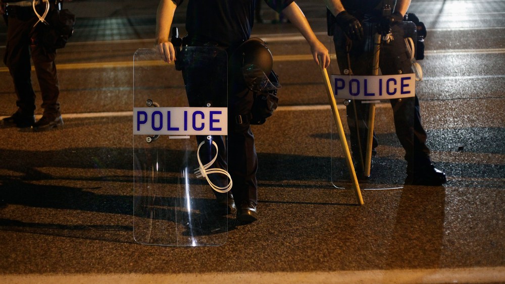 Police officers in riot gear stand in position as demonstrators protest the shooting death of Michael Brown, in Ferguson, Mo., Aug. 19, 2014. (Photo by Joshua Lott/Reuters)
