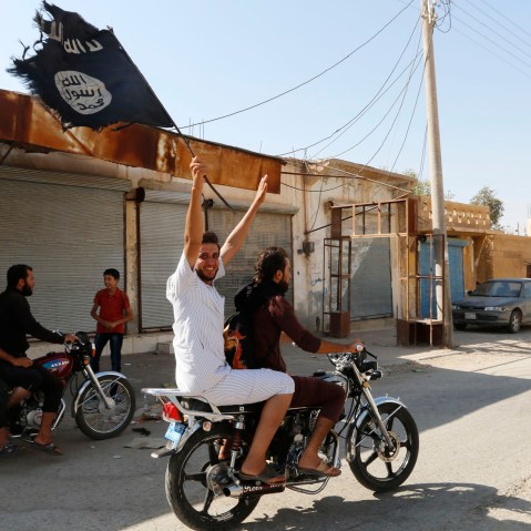 A resident of Tabqa city waves an Islamist flag in celebration after Islamic State militants took over Tabqa air base, in nearby Raqqa city, August 24, 2014.