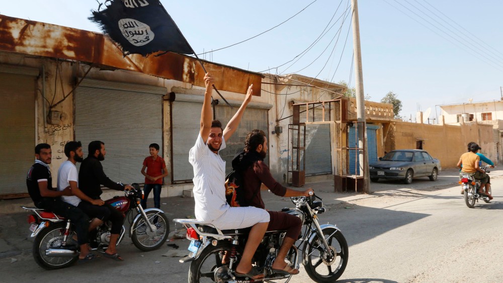 A resident of Tabqa city waves an Islamist flag in celebration after Islamic State militants took over Tabqa air base, in nearby Raqqa city, August 24, 2014.