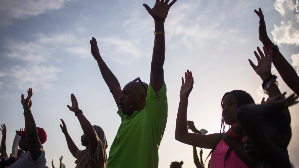 Supporters of Michael Brown, who was killed by a police officer on August 9, raise their hands in solidarity as they are led by Tracy Martin, father of Trayvon Martin, a Florida teenager shot dead in 2012, at the the Peace Fest 2014 rally in St. Louis, Mo