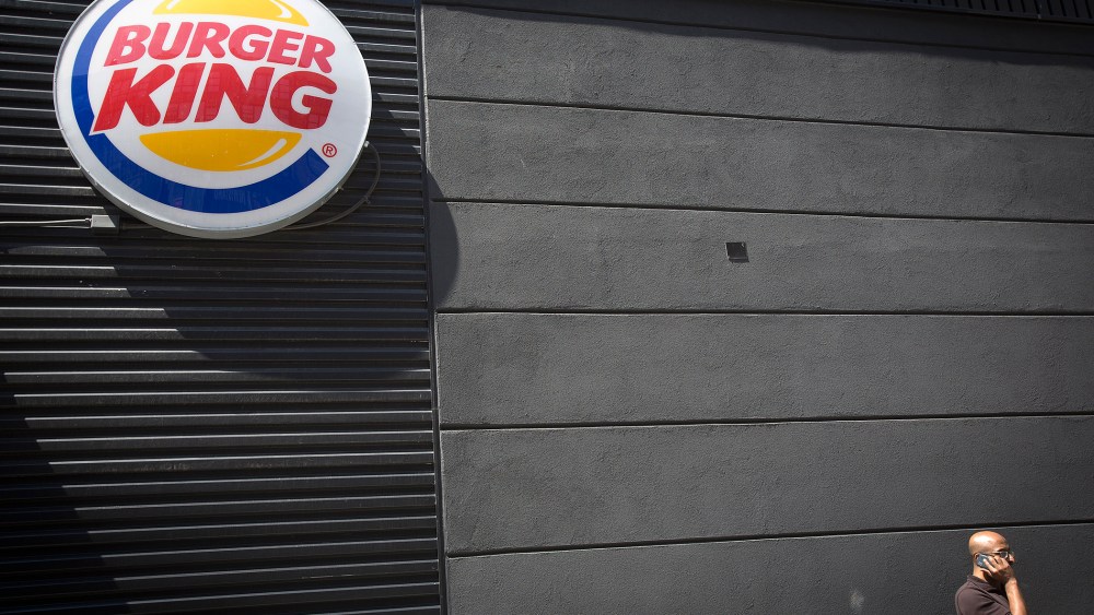 A man talks on his phone underneath a Burger King logo outside the restaurant in the Brooklyn borough of New York