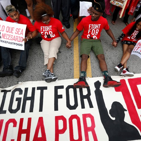 Demonstrators sit down in the middle of the road during a protest at a McDonald's restaurant In Chicago, Ill., Sept. 4, 2014.