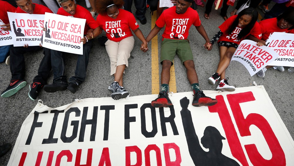 Demonstrators sit down in the middle of the road during a protest at a McDonald's restaurant In Chicago, Ill., Sept. 4, 2014.