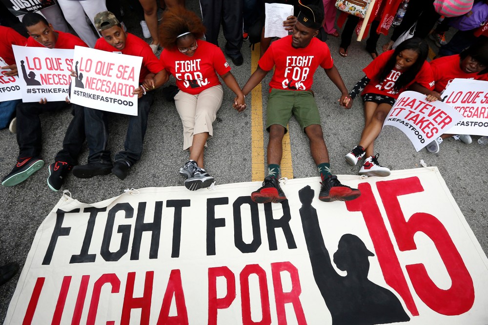 Demonstrators sit down in the middle of the road during a protest at a McDonald's restaurant In Chicago, Ill., Sept. 4, 2014.