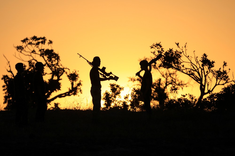 Free Syrian Army fighters carry their weapons on one of the frontlines of Wadi Al-Dayf camp in the southern Idlib countryside