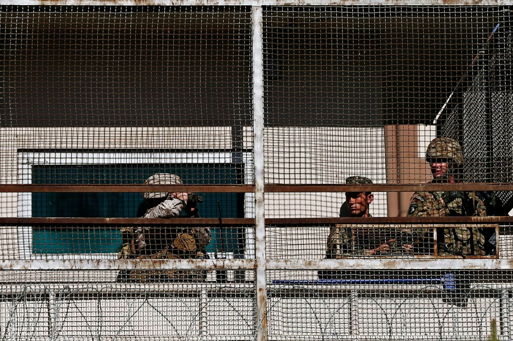 A U.S. soldier (R) and Afghan security forces keep watch from a security tower at the site of a suicide attack in Kabul September 16, 2014.