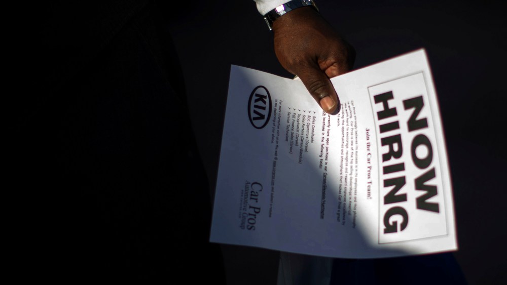 A man holds a leaflet at ' job fair in Carson, Calif. on Oct. 3, 2014