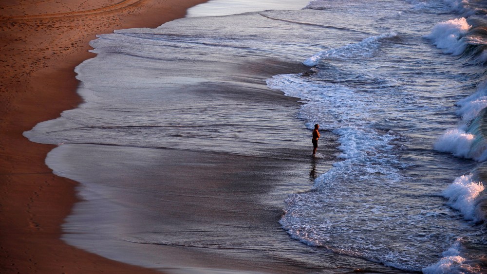 A lone swimmer prepares to enter the surf at sunrise on Sydney's Bondi Beach