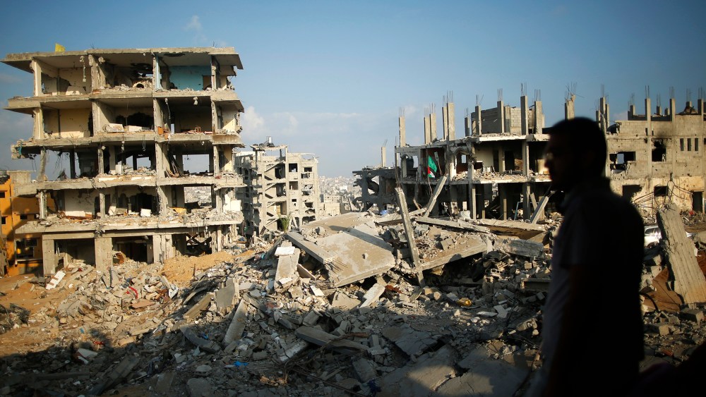A Palestinian man stands atop the rubble of his house as he looks at the ruins of neighboring houses that witnesses said were destroyed or damaged during the 50-day war between the Hamas militant movement and Israel, in the east of Gaza City.