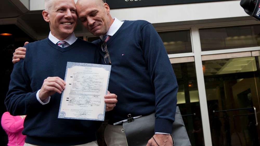 Terrence Hall (L) and Christopher DeCaria (R) display their marriage license to the media outside of the Mecklenburg County Register of Deeds office in Charlotte, North Carolina, on Oct. 13, 2014.
