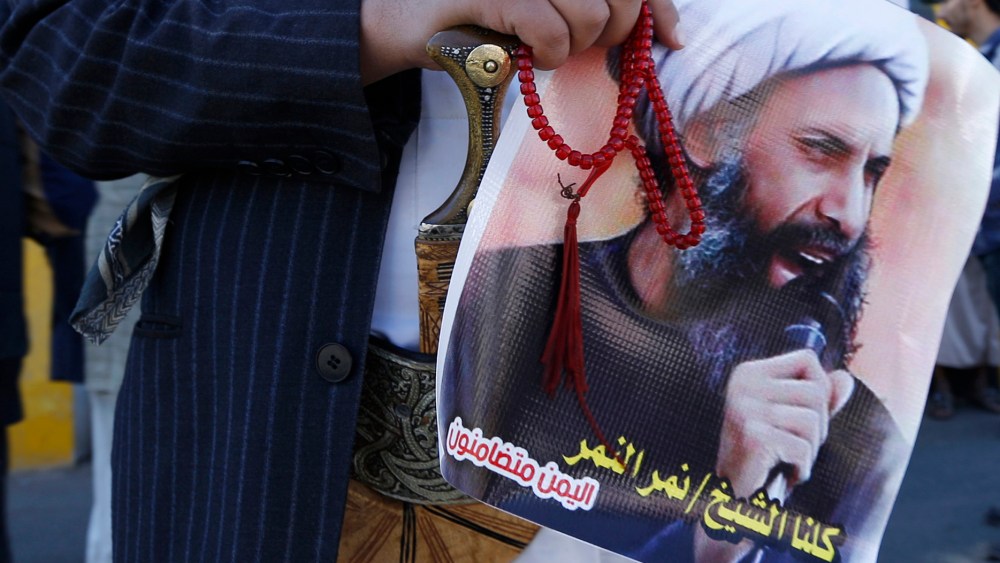 A Shi'ite protester carries a poster of Sheikh Nimr al-Nimr during a demonstration outside the Saudi embassy in Sanaa, Oct. 18, 2014. (Photo by Khaled Abdullah/Reuters)