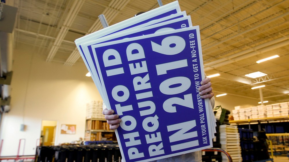 A worker carries a sign that will be displayed at a polling place that will inform voters of the new voter ID law that goes into effect in 2016 at the Mecklenburg County Board of Elections warehouse in Charlotte, N.C., Nov. 3, 2014.