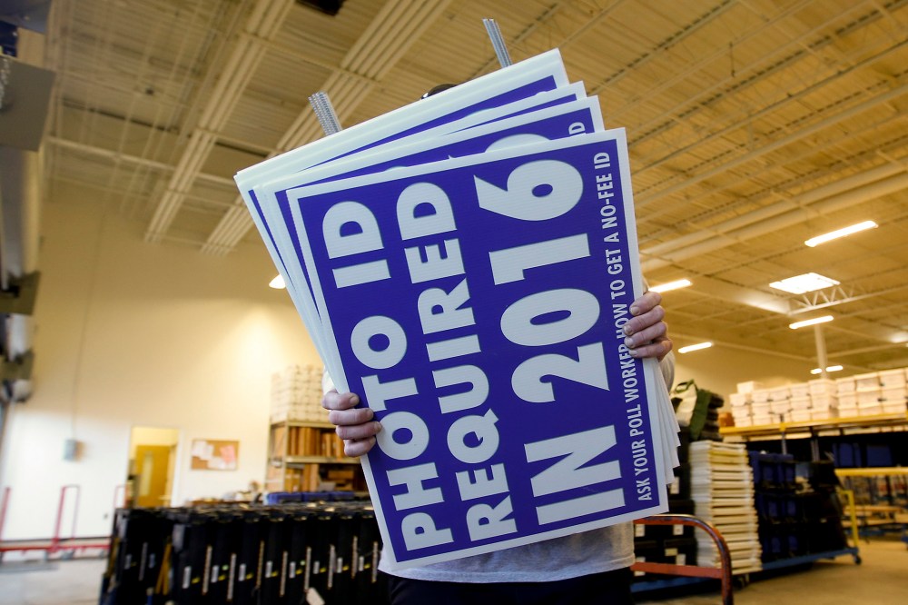 A worker carries a sign that will be displayed at a polling place that will inform voters of the new voter ID law that goes into effect in 2016 at the Mecklenburg County Board of Elections warehouse in Charlotte, N.C., Nov. 3, 2014.