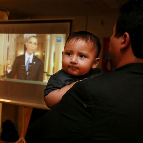 Christian Ramirez holds his nine-month old son Diego while watching President Barack Obama's White House speech on immigration at a viewing party at Alliance San Diego in San Diego, Calif., Nov. 20, 2014. (Photo by Sandy Huffaker/Reuters)