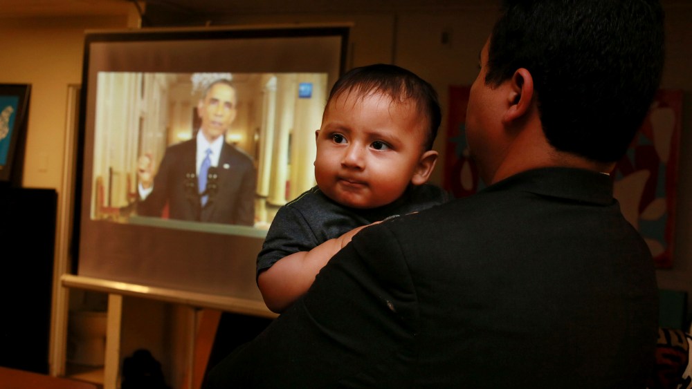 Christian Ramirez holds his nine-month old son Diego while watching President Barack Obama's White House speech on immigration at a viewing party at Alliance San Diego in San Diego, Calif., Nov. 20, 2014. (Photo by Sandy Huffaker/Reuters)