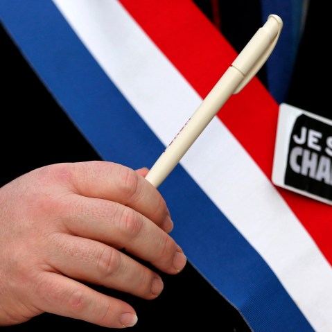 A man holds a pen and wears a sticker reading "Je suis Charlie" during a march for the victims of the shootings by gunmen at the offices of the satirical weekly newspaper Charlie Hebdo in Paris, in Brussels