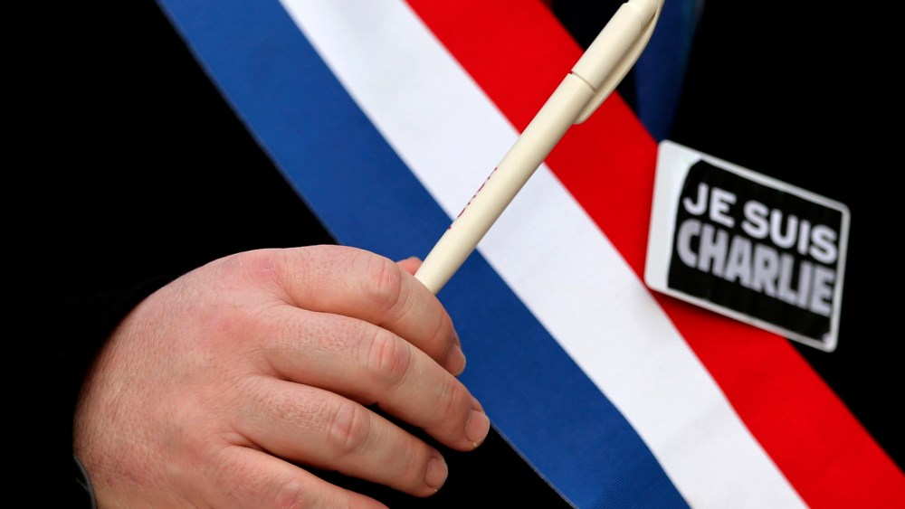 A man holds a pen and wears a sticker reading "Je suis Charlie" during a march for the victims of the shootings by gunmen at the offices of the satirical weekly newspaper Charlie Hebdo in Paris, in Brussels