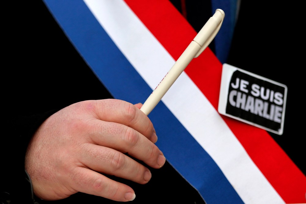 A man holds a pen and wears a sticker reading "Je suis Charlie" during a march for the victims of the shootings by gunmen at the offices of the satirical weekly newspaper Charlie Hebdo in Paris, in Brussels