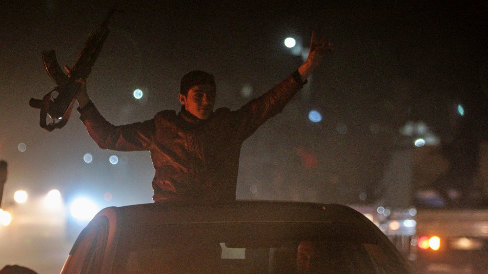 A Kurdish man holds up a weapon as he tours with others the streets of Ras al-Ain in celebration, after it was reported that Kurdish forces took control of the Syrian town of Kobani, Jani 26, 2015.
