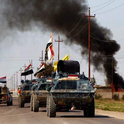 Armored vehicles of Iraqi security forces with militias known as Hashid Shaabi are driven past smoke arising from a clash with Islamic State militants in the town of al-Alam, Tikrit, March 10, 2015. (Photo by Thaier Al-Sudani/Reuters)