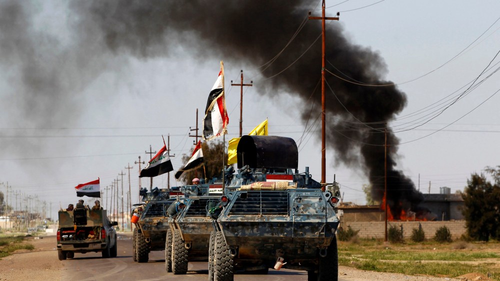 Armored vehicles of Iraqi security forces with militias known as Hashid Shaabi are driven past smoke arising from a clash with Islamic State militants in the town of al-Alam, Tikrit, March 10, 2015. (Photo by Thaier Al-Sudani/Reuters)