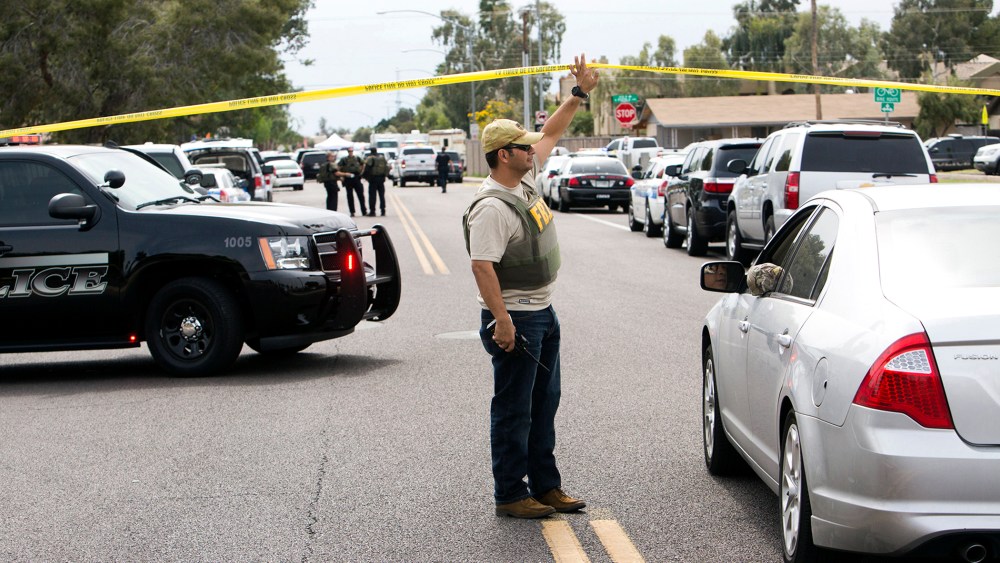 An FBI agent lifts police tape at one of the scenes of a multiple location shooting that has injured at least four people in Mesa, Arizona on March 18, 2015. (Photo by Deanna Dent/Reuters)