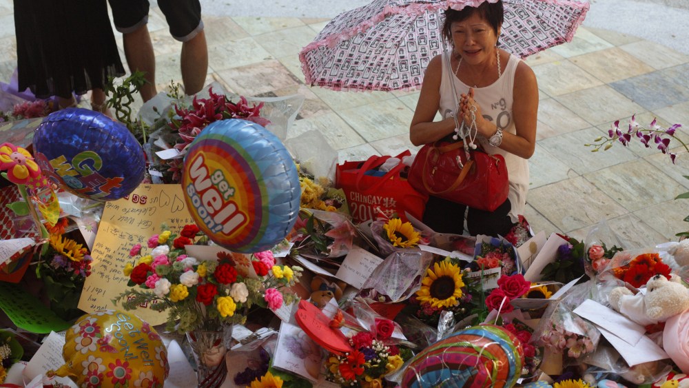 A woman weeps as she prays in the rain at a well-wishing corner for Singapore's former Prime Minister Lee Kuan Yew at the Singapore General Hospital March 22, 2015. (Photo by Edgar Su/Reuters)
