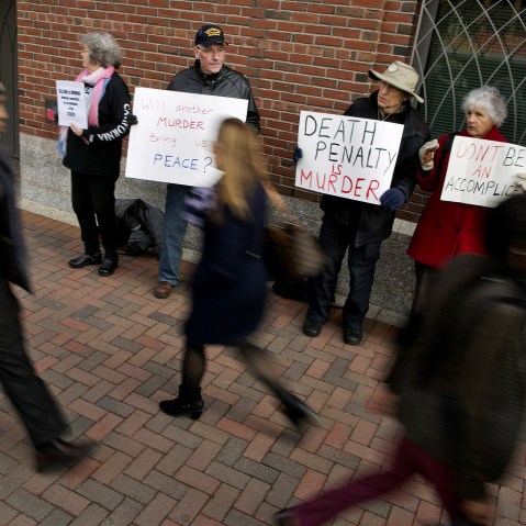 Pedestrians pass by protesters against the death penalty before closing arguments in the trial of accused Boston Marathon bomber Dzhokhar Tsarnaev at the federal courthouse in Boston, Massachusetts on April 6, 2015. (Photo by Dominick Reuter/Reuters)