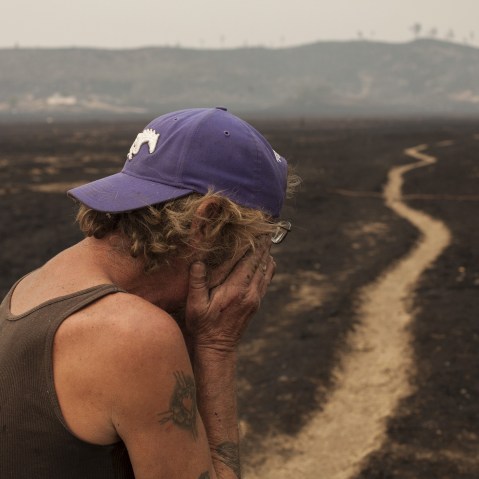 Robert Hooper, exhausted after several days with little sleep, is overcome with emotion while surveying what's left of his property near Middleton, Calif. Sept. 14, 2015. (Photo by David Ryder/Reuters)
