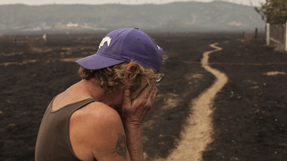 Robert Hooper, exhausted after several days with little sleep, is overcome with emotion while surveying what's left of his property near Middleton, Calif. Sept. 14, 2015. (Photo by David Ryder/Reuters)