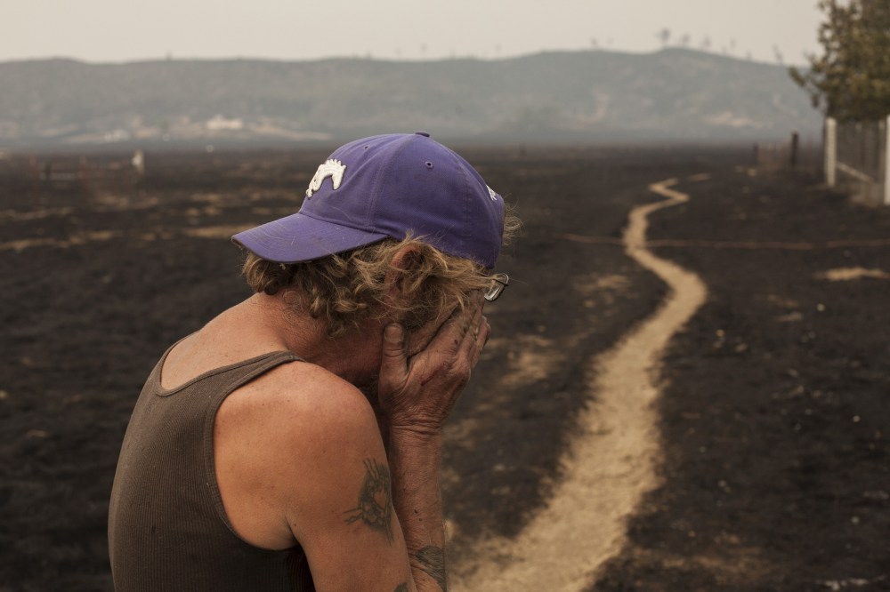 Robert Hooper, exhausted after several days with little sleep, is overcome with emotion while surveying what's left of his property near Middleton, Calif. Sept. 14, 2015. (Photo by David Ryder/Reuters)