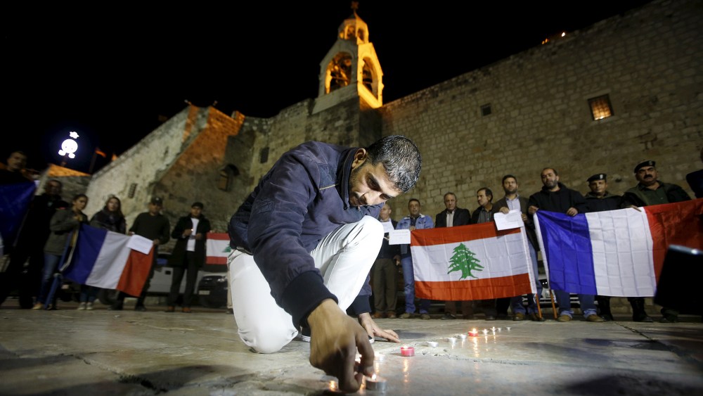 A Palestinian lights a candle during a rally in solidarity with victims of Paris attacks and recent Lebanon bombing, in front of the Nativity church in the West Bank city of Bethlehem, Nov. 14, 2015. (Photo by Mussa Qawasma/Reuters)