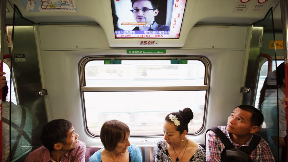 Passengers watch a television screen broadcasting news on Edward Snowden on a train in Hong Kong June 14, 2013.