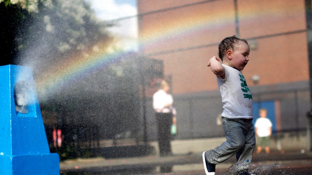 A young boy cools off in the water from a playground sprinkler in the Brooklyn borough of New York