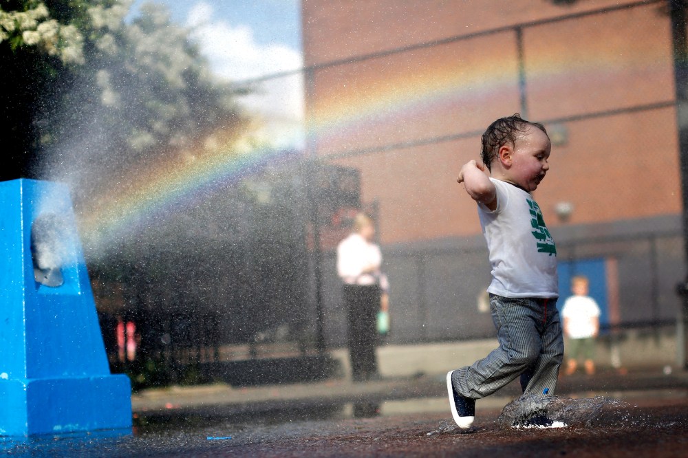 A young boy cools off in the water from a playground sprinkler in the Brooklyn borough of New York