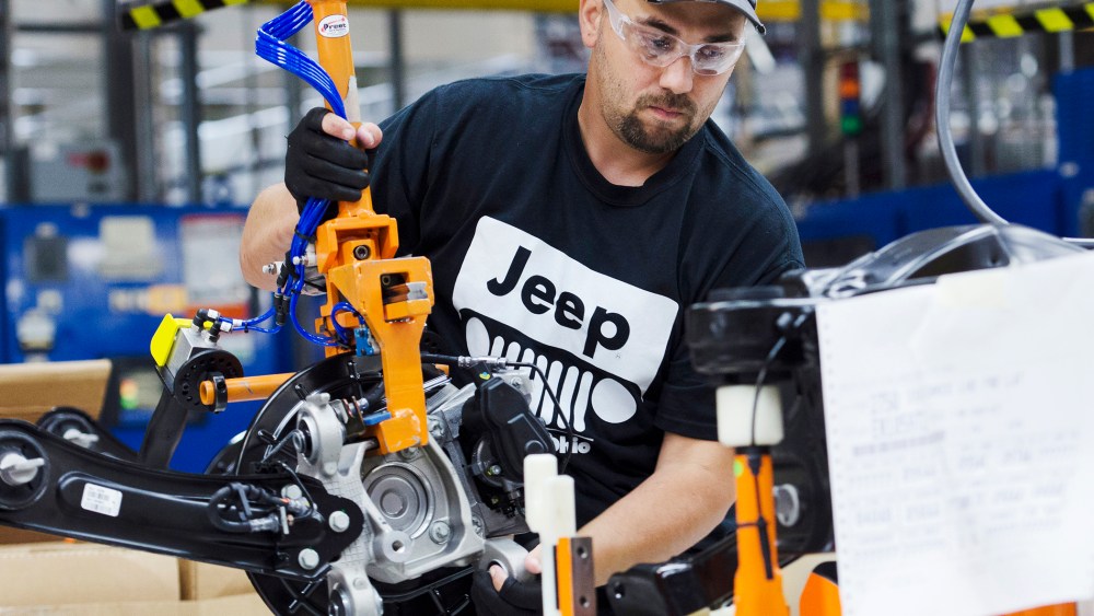 A production line worker installs a brake and rotor unit are on the rear axle assembly of a 2014 Jeep Cherokee at the Chrysler Toledo Assembly Complex in Toledo, Ohio on July 18, 2013.