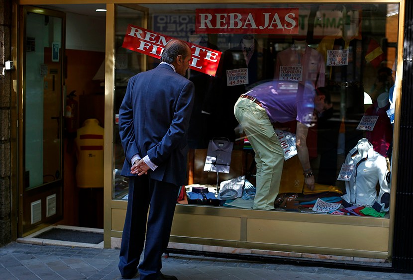 A man window shops as a worker changes the price tags of clothing items at a store in Madrid July 31, 2013. (Photo by Susana Vera/Reuters)