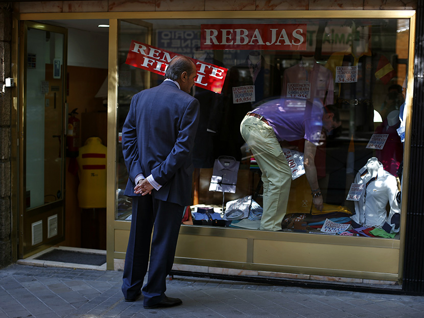 A man window shops as a worker changes the price tags of clothing items at a store in Madrid July 31, 2013. (Photo by Susana Vera/Reuters)
