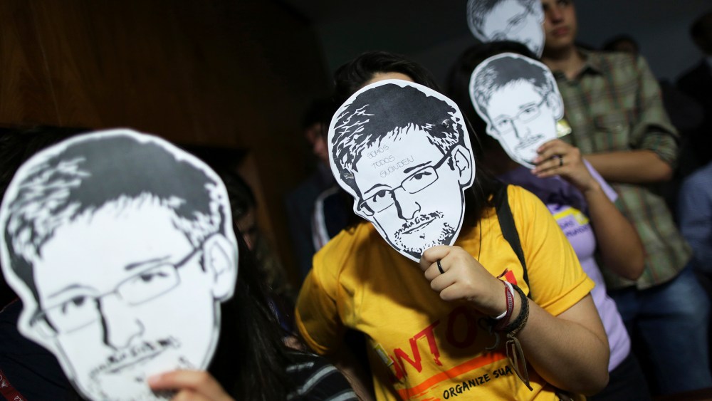 People use masks with pictures of Snowden masks during the testimonial of Greenwald before a Brazilian Congressional committee, Aug. 6, 2013.