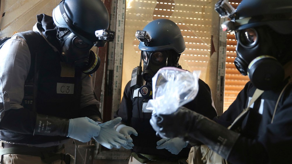 A U.N. chemical weapons expert holds a plastic bag containing samples from one of the sites of an alleged chemical weapons attack in Ain Tarma
