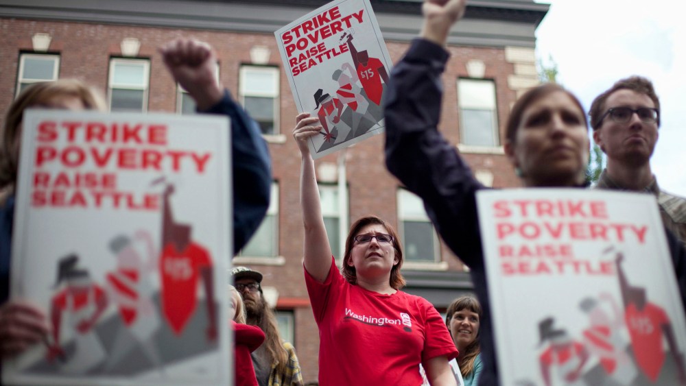 Joelle Craft (C) holds a sign during a rally and strike aimed at the fast-food industry and the minimum wage in Seattle, Washington, Aug. 29, 2013.