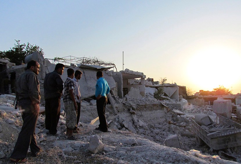Residents inspect buildings damaged by what activists said were warplanes belonging to forces loyal to Syria's president Al-Assad in Iskat