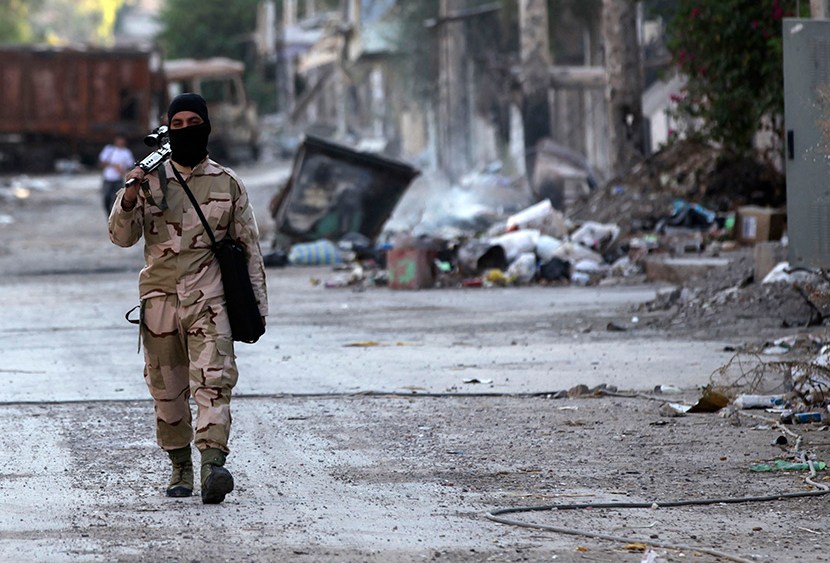 A Free Syrian Army fighter walks with his weapon on a street in Deir al-Zor