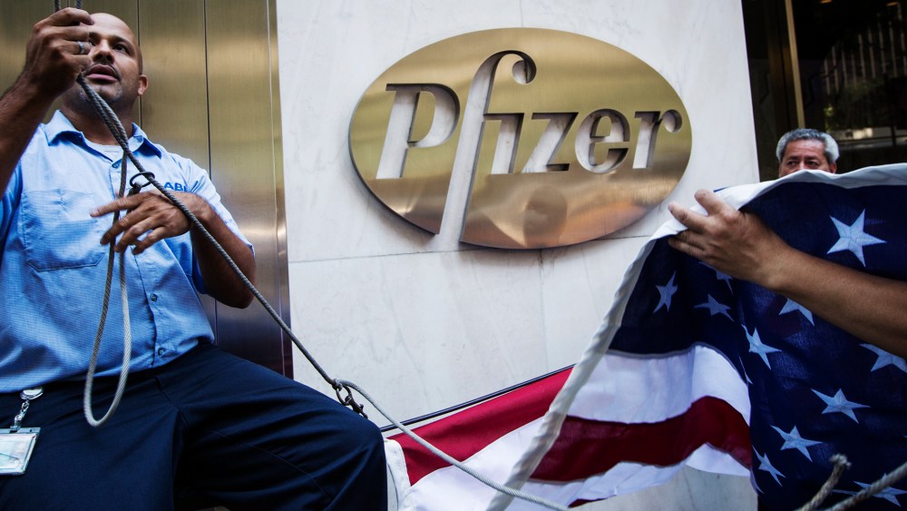Workers raise a U.S. flag outside the Pfizer building in New York on Sept. 4, 2013.